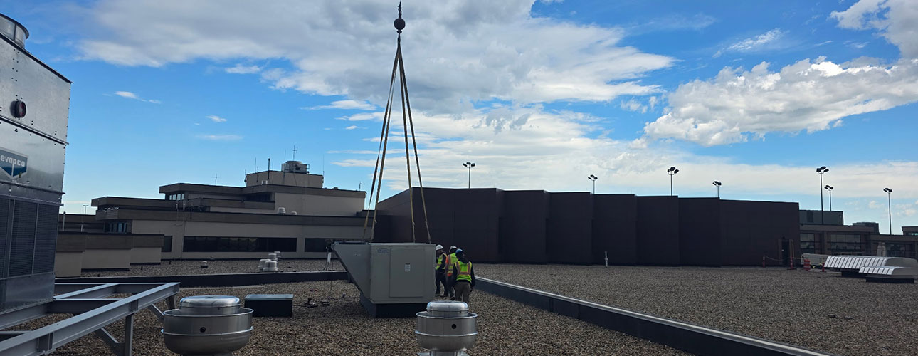 Precision Mechanical using a crane to put an HVAC unit on a commercial building
